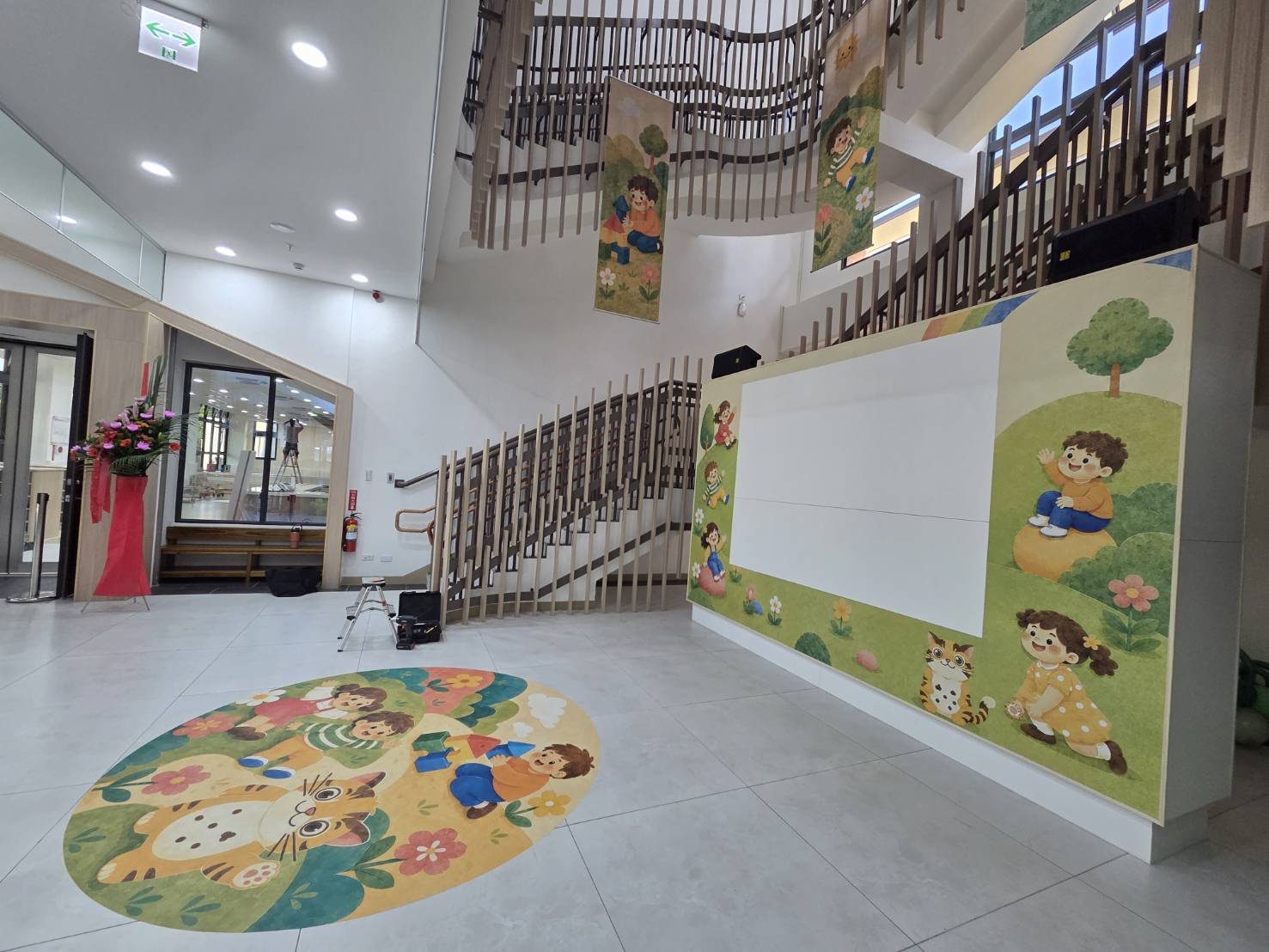 苗栗親子館暨托嬰中心大廳全景,入口地貼、投影牆與天井旗幟一次到位